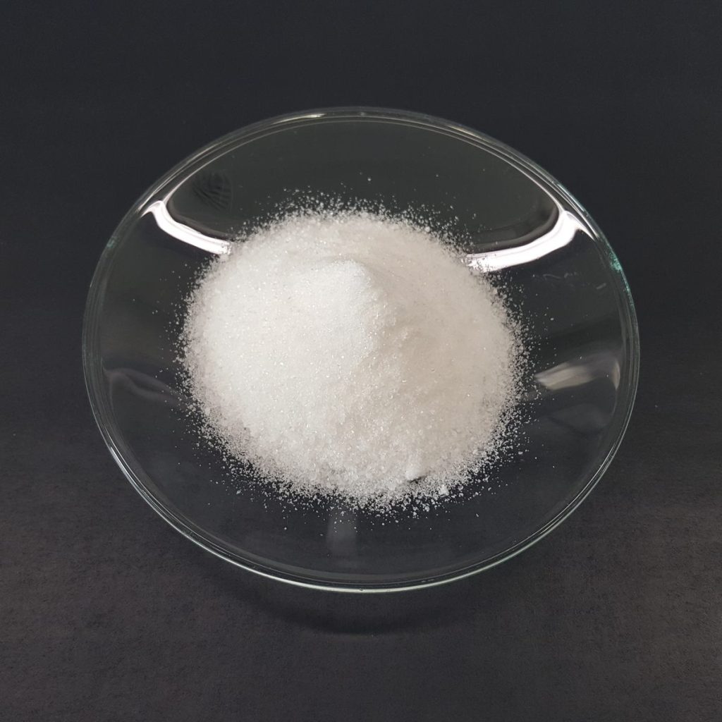 Poudre protéinée blanche et fine versée dans une coupelle en verre, texture d'une whey isolate
