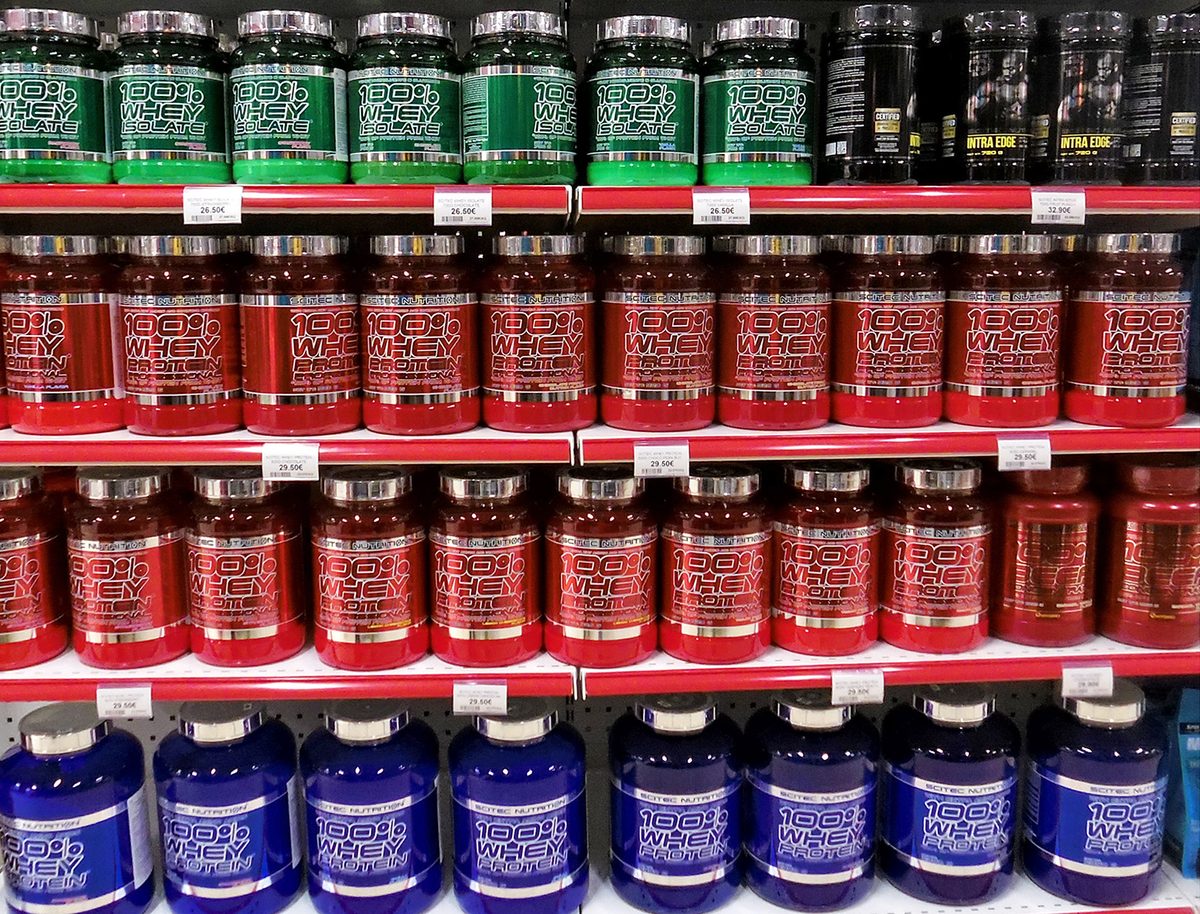 Rayon de compléments alimentaires en magasin, pots de protéines alignés sur les étagères